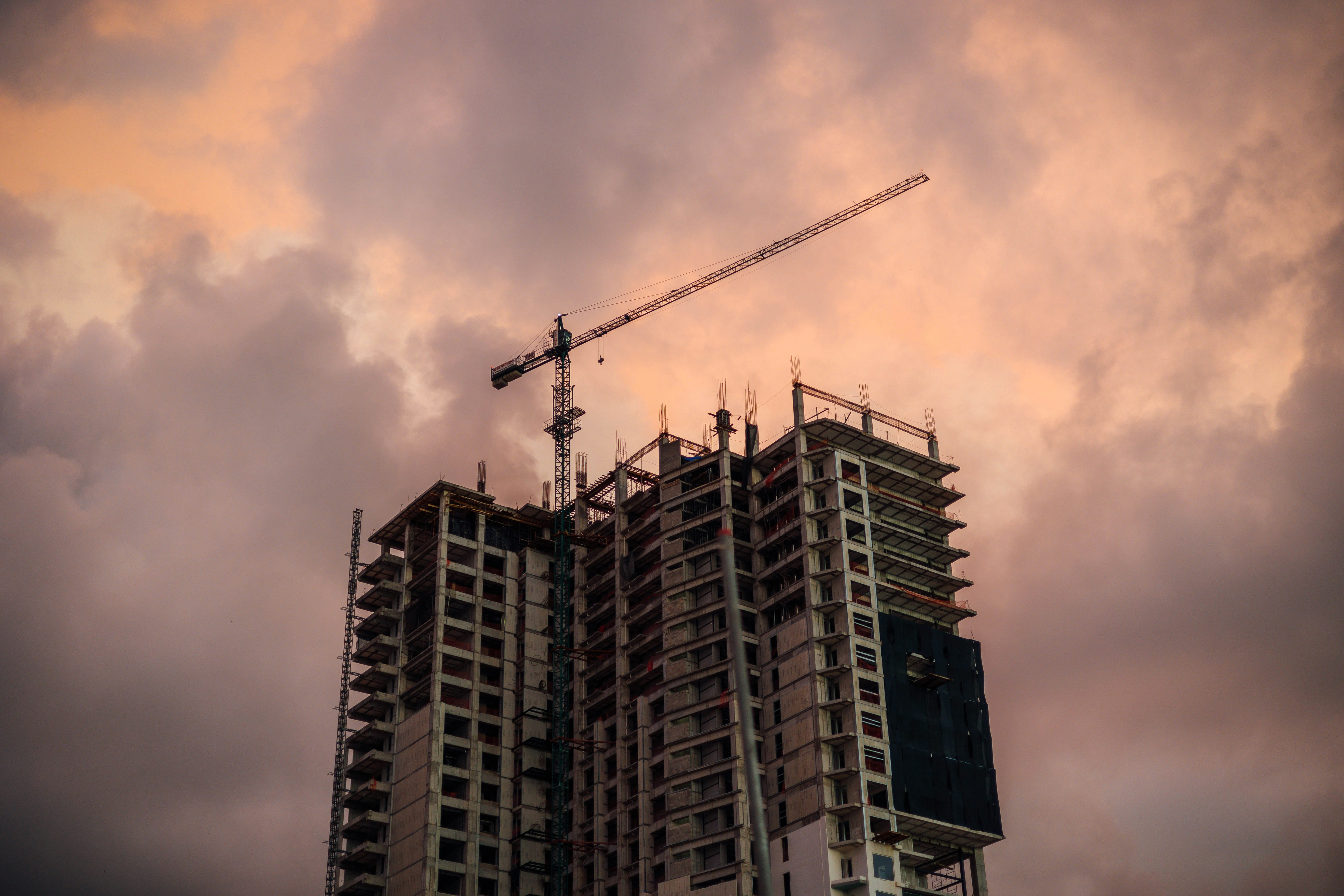 a crane on top of a tall building under a cloudy sky