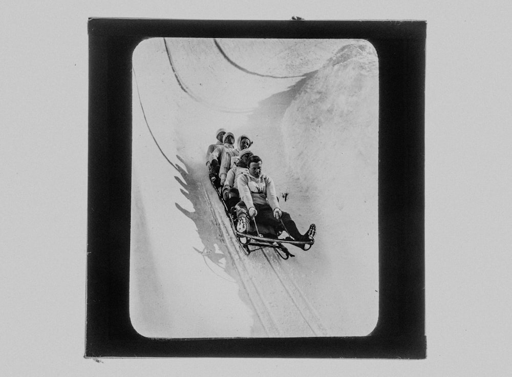 a group of people riding a sled down a snow covered slope