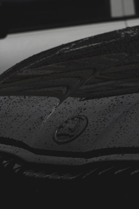 Close-up of a sleek black sports car hood with water droplets glistening after detailing.