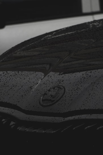 Close-up of a car hood protected by a clear PPF film showing water beading.