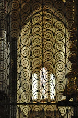 Artisan hands finishing a delicate iron scrollwork piece under focused lighting.