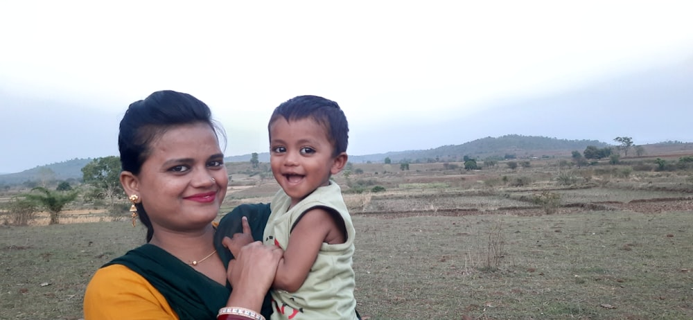 a woman holding a child in a field