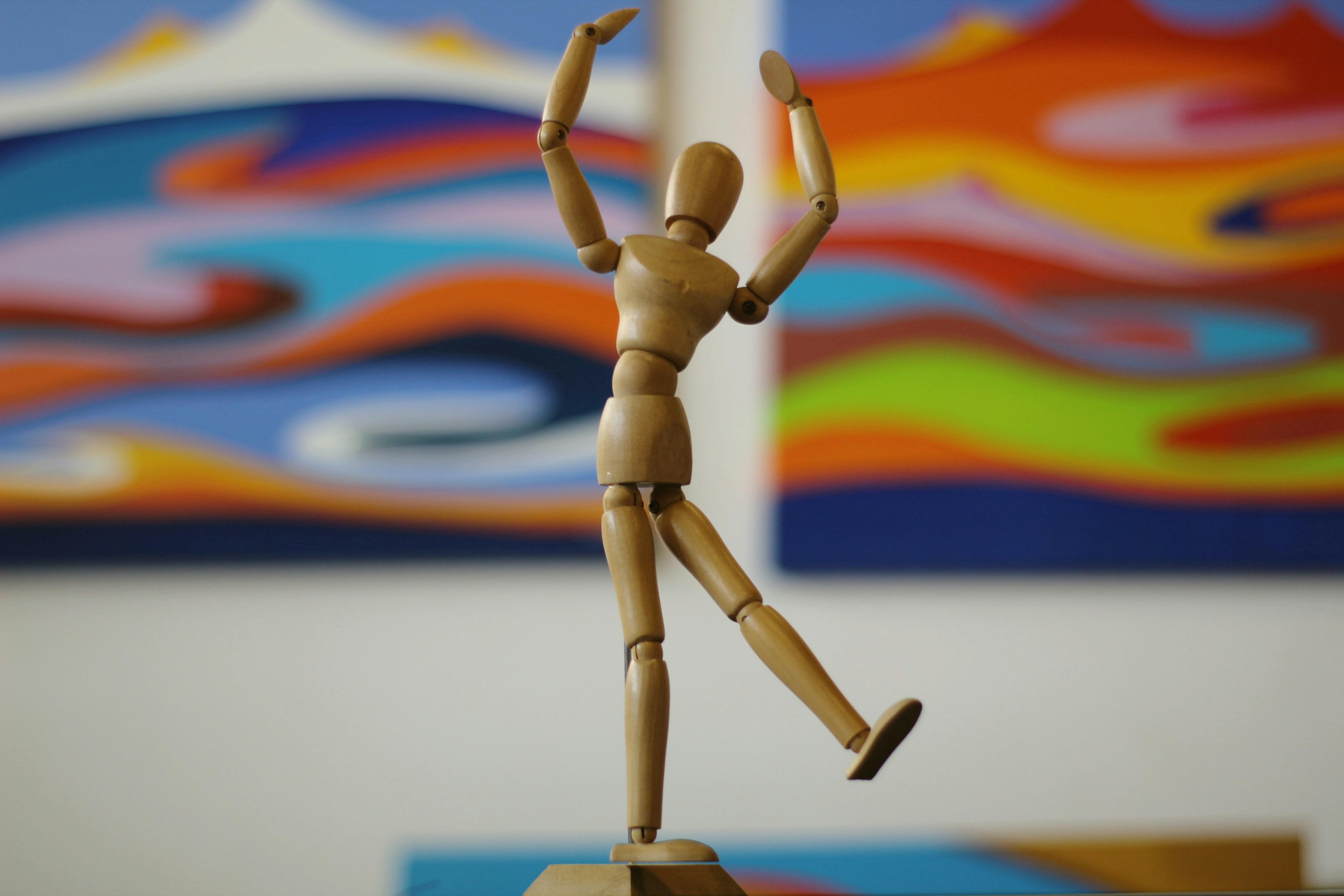 A wooden mannequin posed in front of a painting