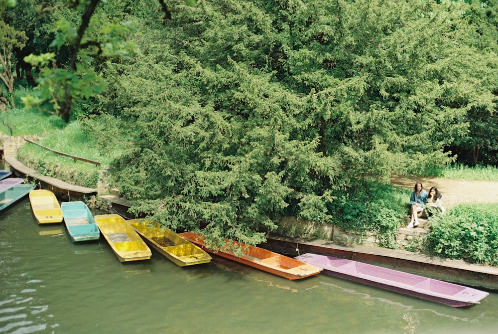 a group of boats sitting on top of a river next to a lush green forest
