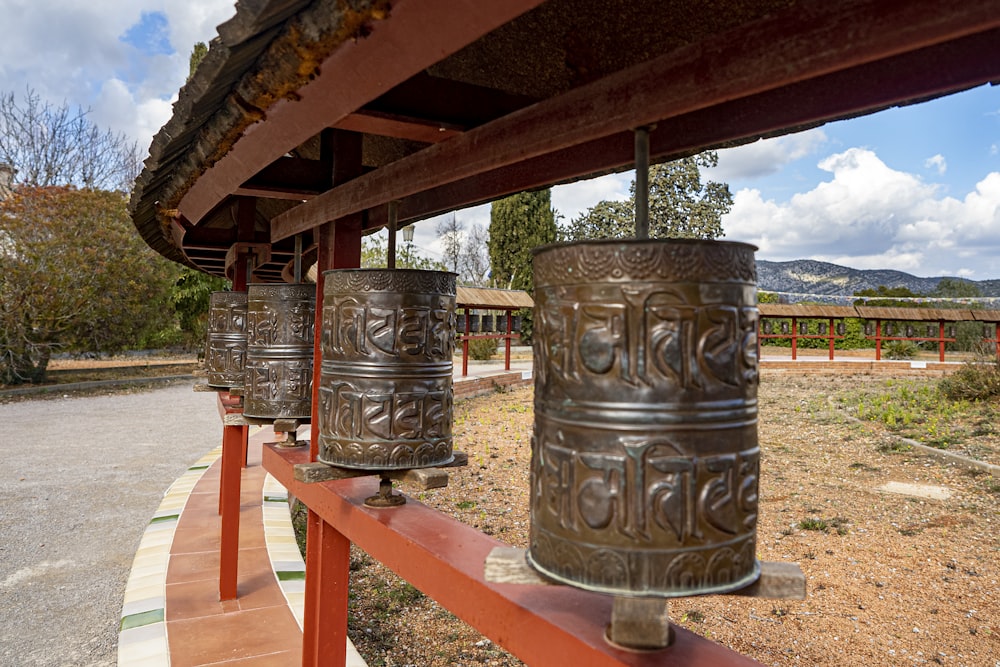 a row of metal bells sitting on top of a wooden fence