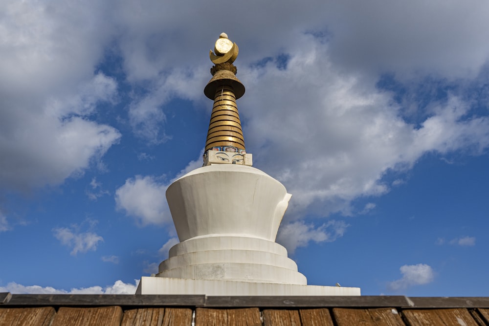 a white and gold statue on top of a wooden structure
