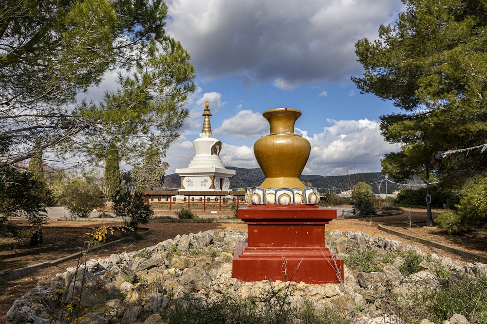 a large golden vase sitting on top of a red pedestal