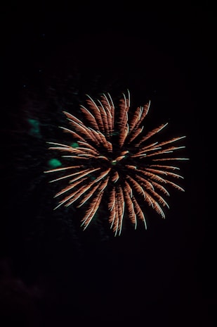 A smoky trail illuminated by glowing neon green and gold fireworks in mid-air.