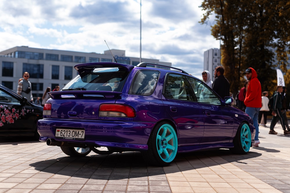 a purple car with blue rims parked in a parking lot