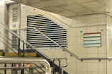 a metal hand rail next to a white tiled wall
