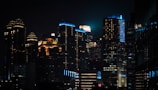 Futuristic cityscape at night illuminated by shiny sky blue and orange neon lights.