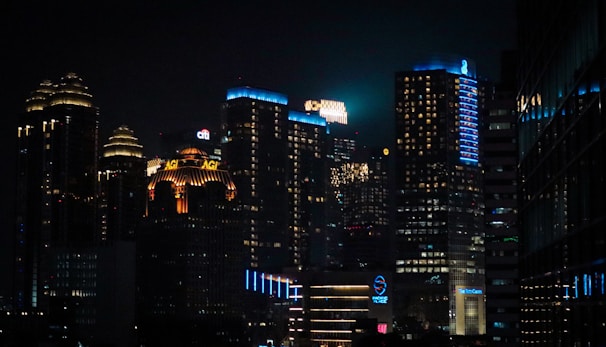 A nighttime cityscape showcasing skyscrapers with glowing lights in black and gold hues.
