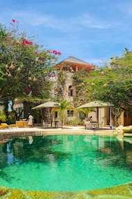 a pool surrounded by lush green trees next to a building