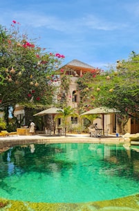 a pool surrounded by lush green trees next to a building