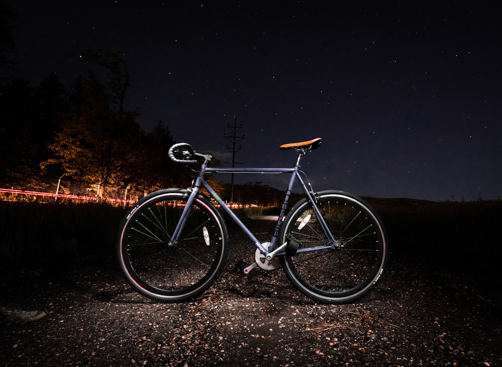 a bicycle parked on a gravel road at night