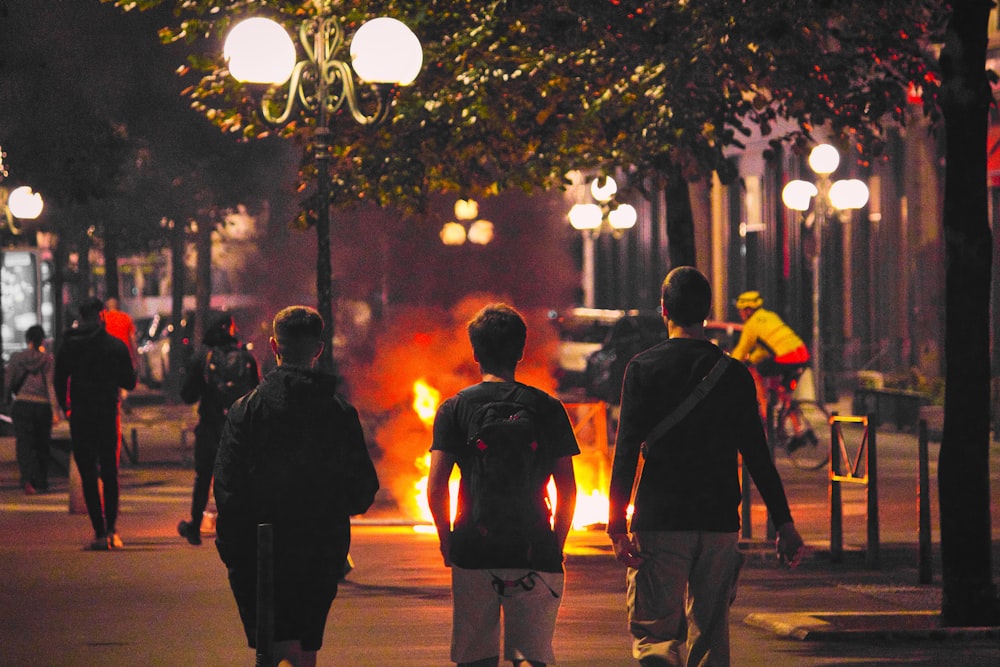 a group of people walking down a street at night