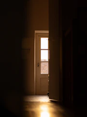 Soft glowing light behind a closed door, hinting at something to come.