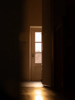Soft glowing light behind a closed door, hinting at something to come.