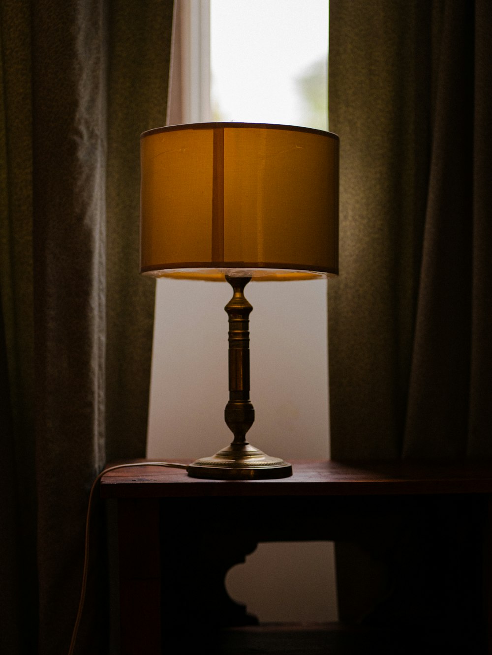 a lamp sitting on top of a table next to a window