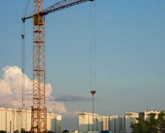 An architect reviewing blueprints at a construction site with cranes in the background.