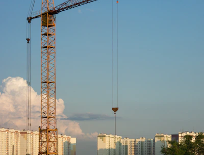 An architect reviewing blueprints at a construction site with cranes in the background.