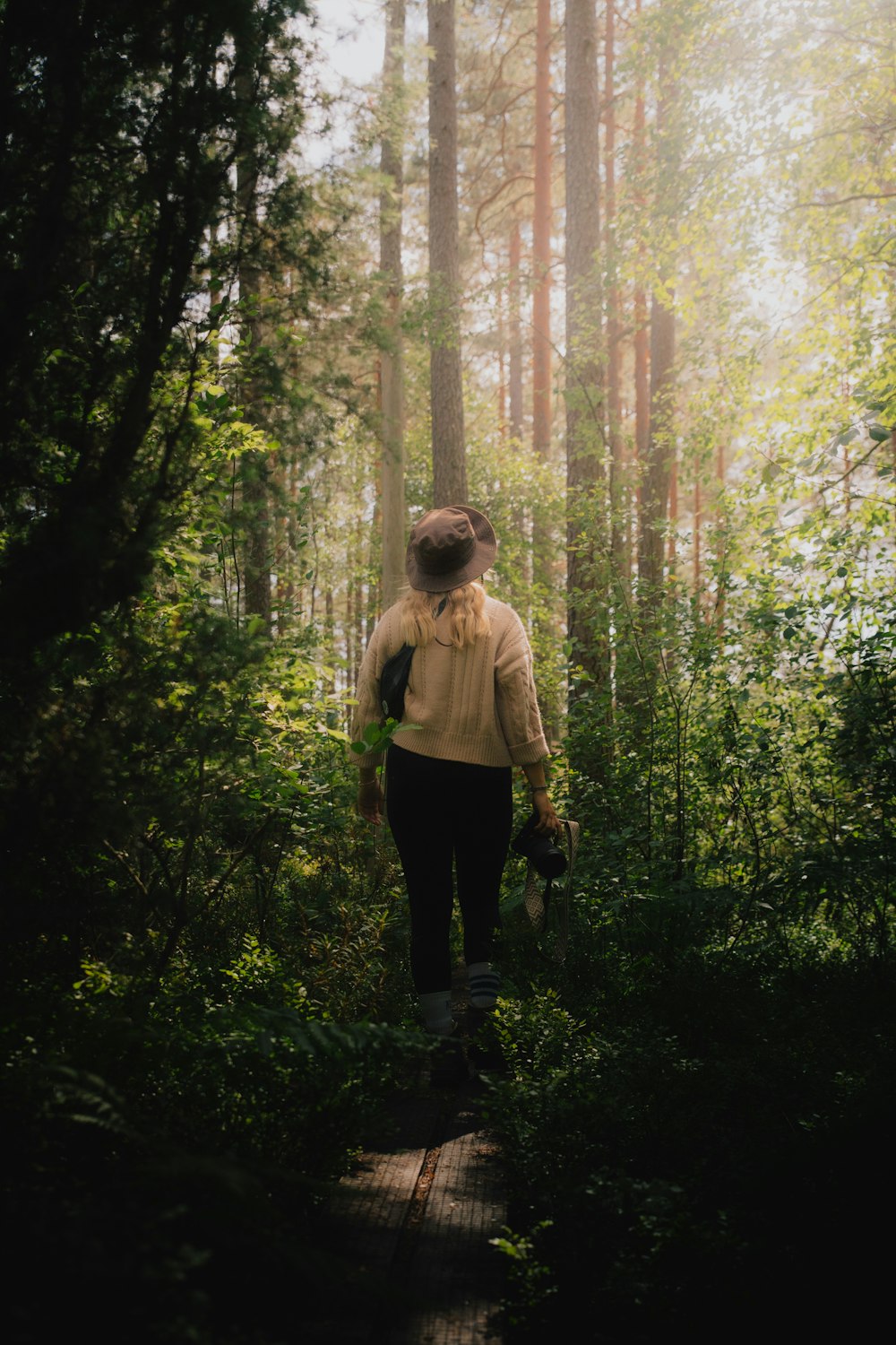 a woman walking through a forest with a backpack
