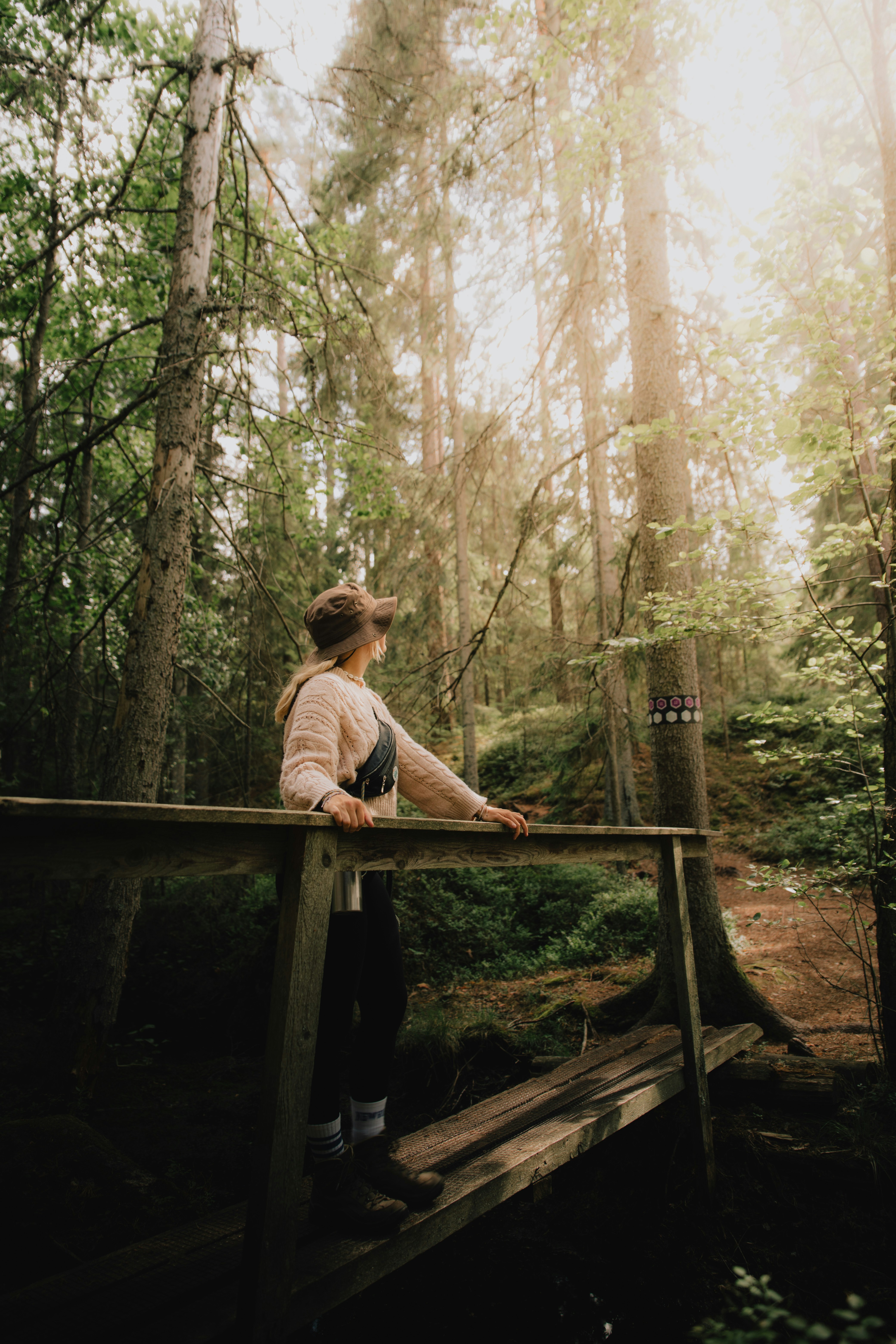 a woman standing on a wooden bridge in the woods