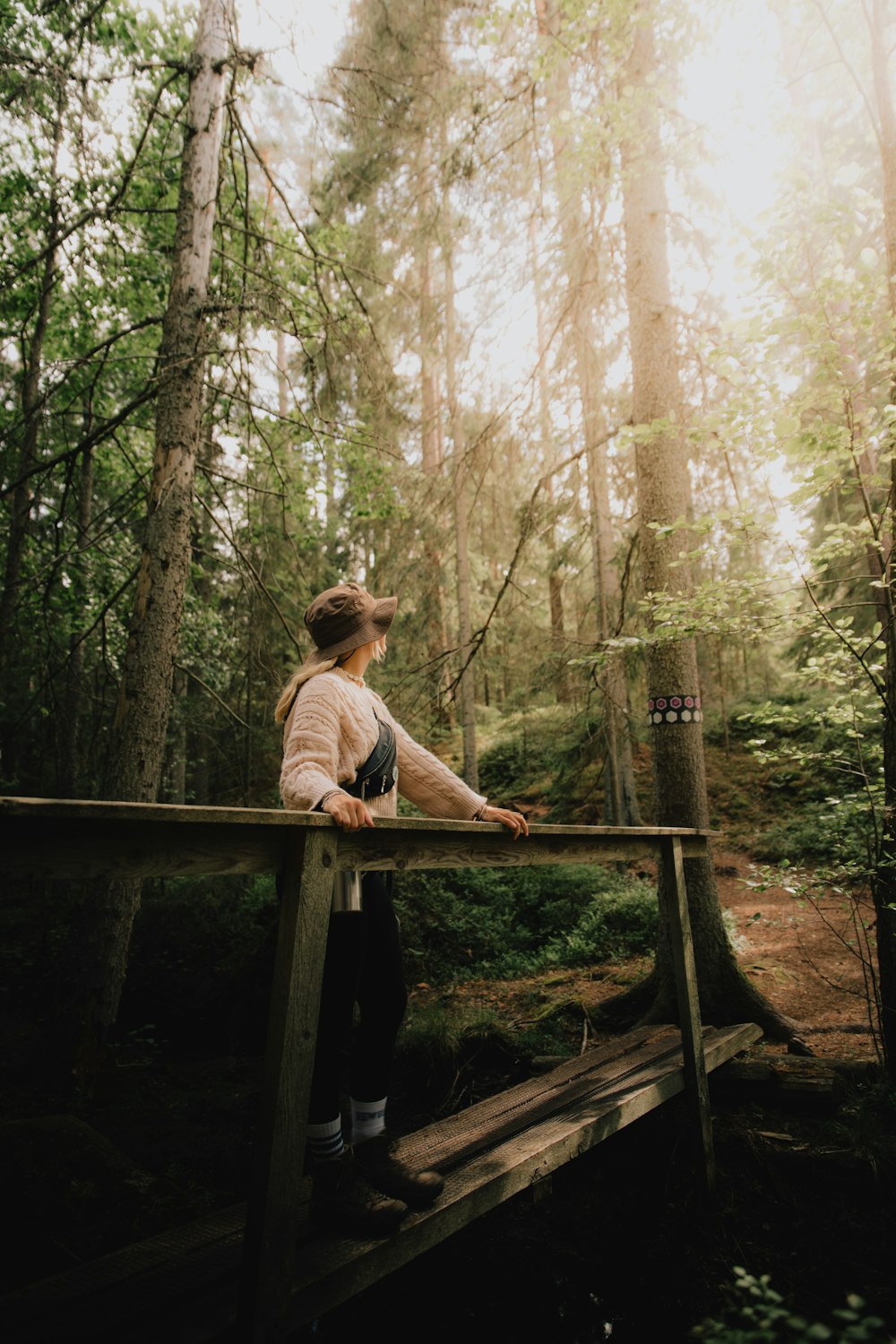 a woman standing on a wooden bridge in the woods