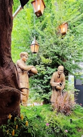 a couple of statues sitting next to a tree