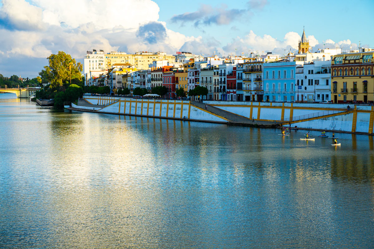 Seville's colourful Triana riverfront seen across the Guadalquivir with rowers on the water