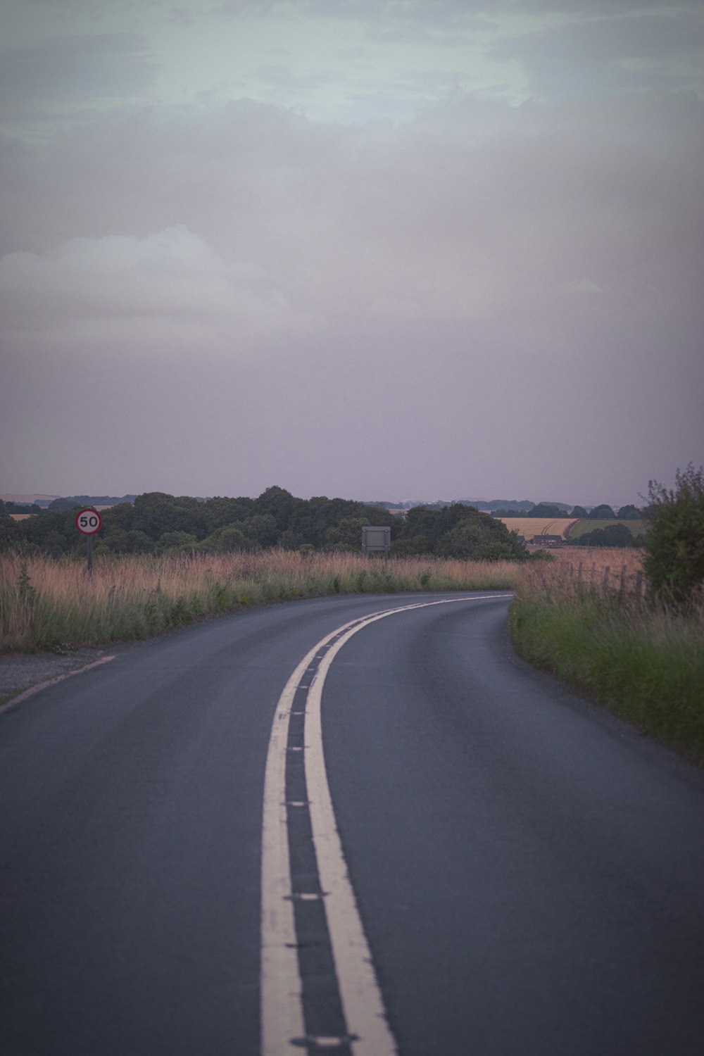 an empty road with a stop sign in the distance