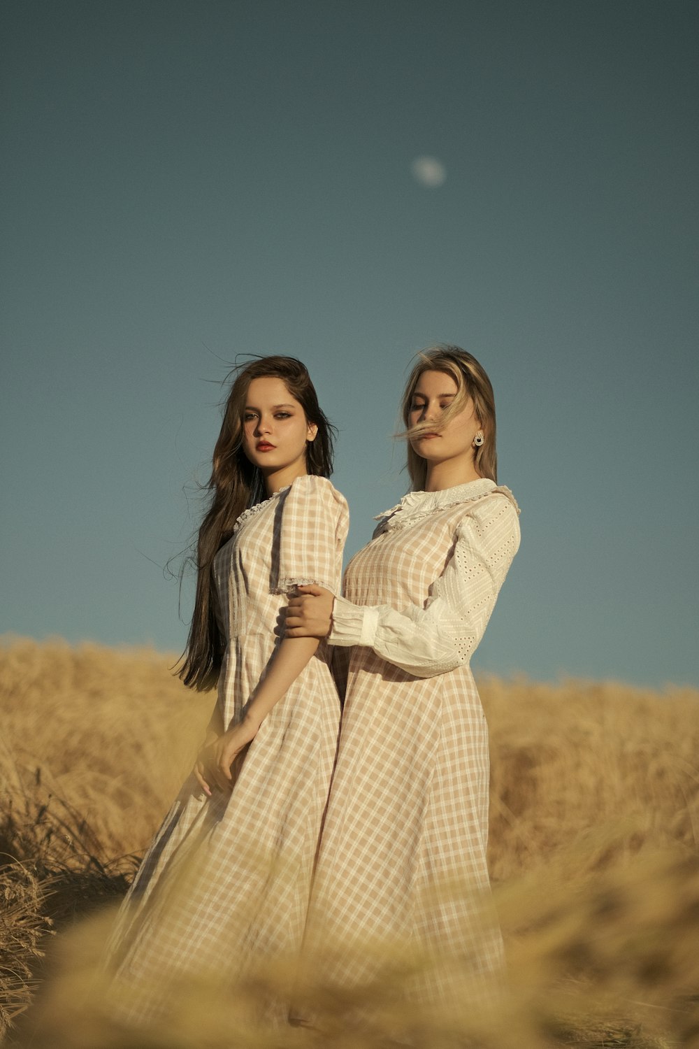 two young women standing in a wheat field