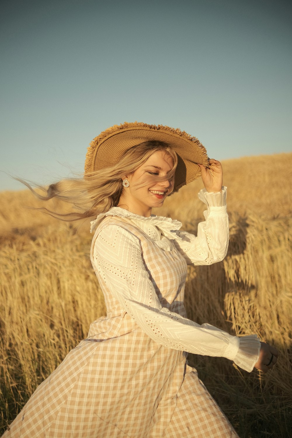 a woman in a dress and hat in a field