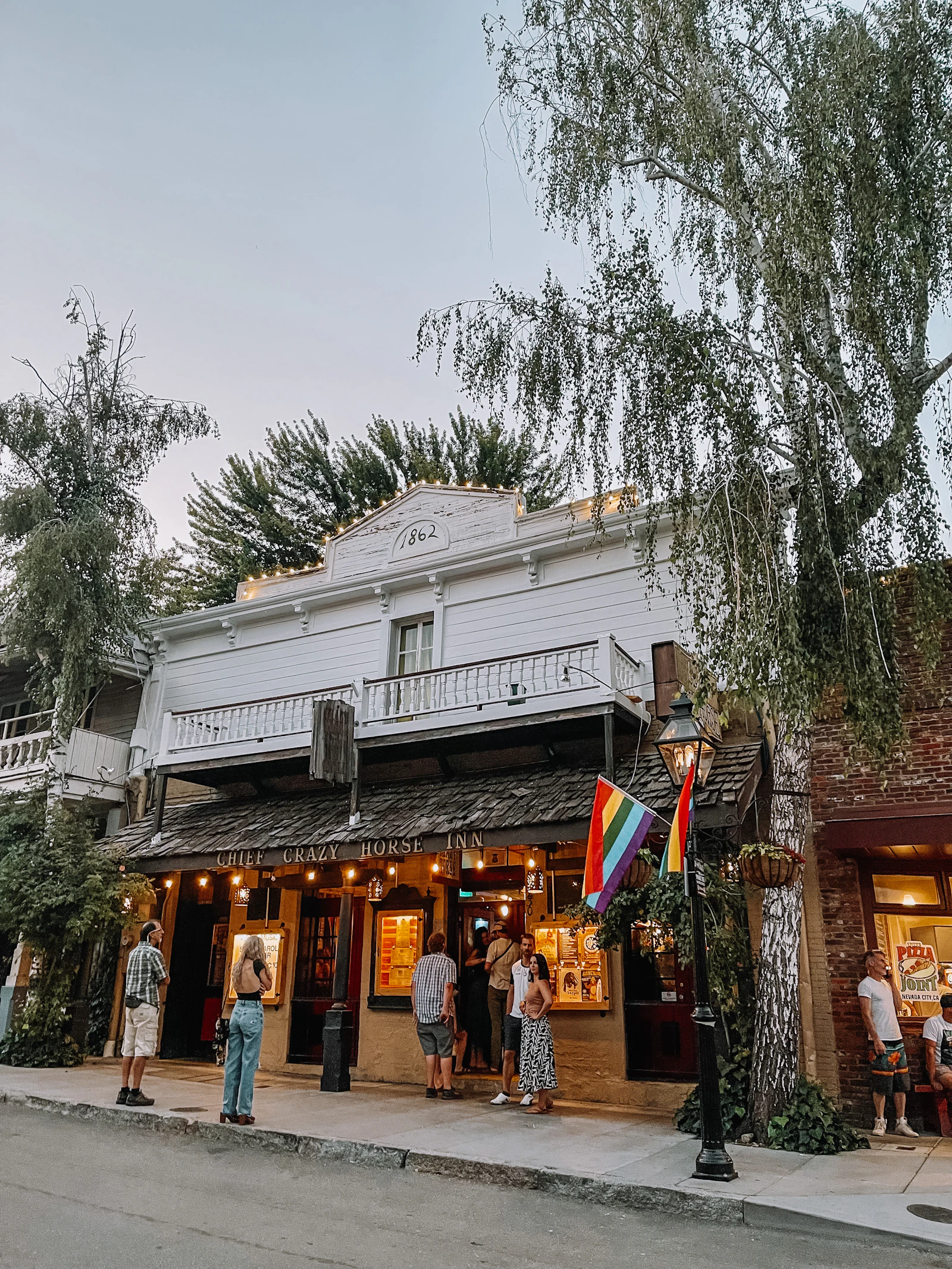 Historic downtown Nevada City street at dusk with visitors gathered outside lit storefronts