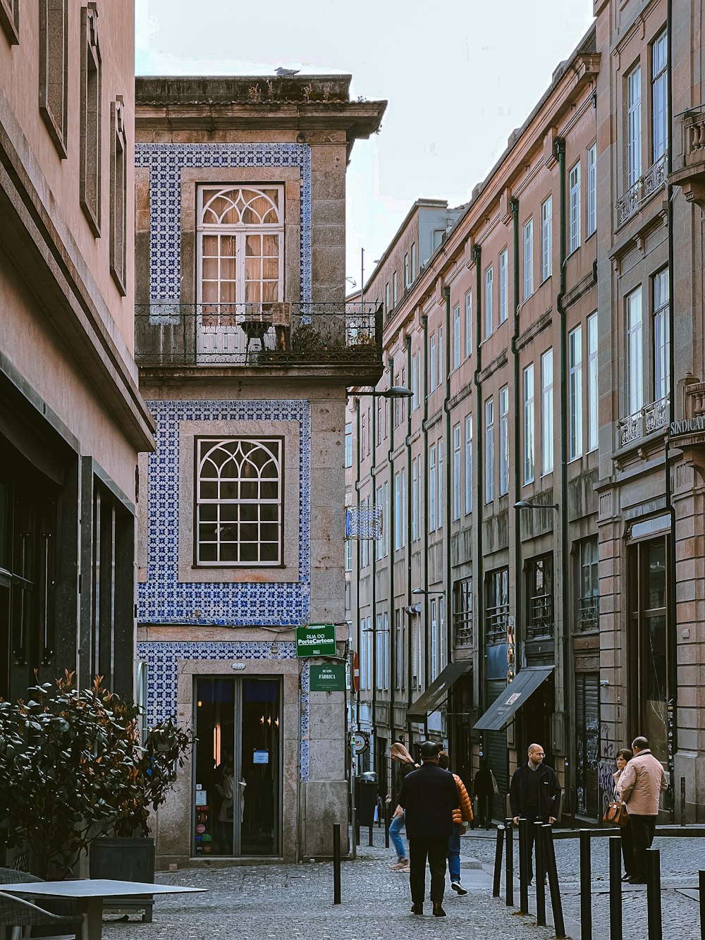 a group of people walking down a street next to tall buildings