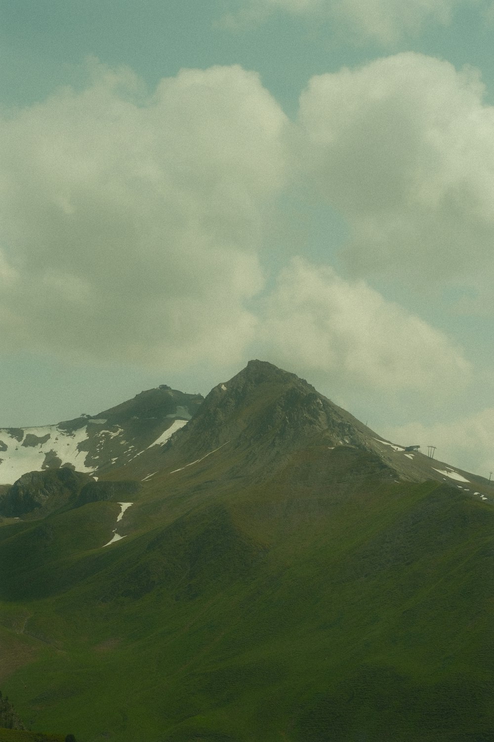 a mountain covered in snow under a cloudy sky