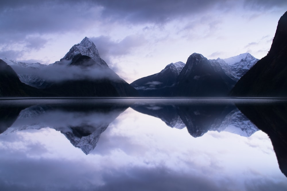 a mountain range is reflected in the still water of a lake