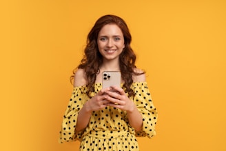 a woman in a yellow polka dot dress holding a cell phone