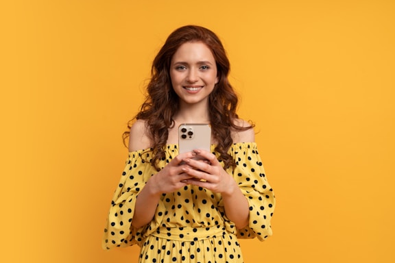 a woman in a yellow polka dot dress holding a cell phone