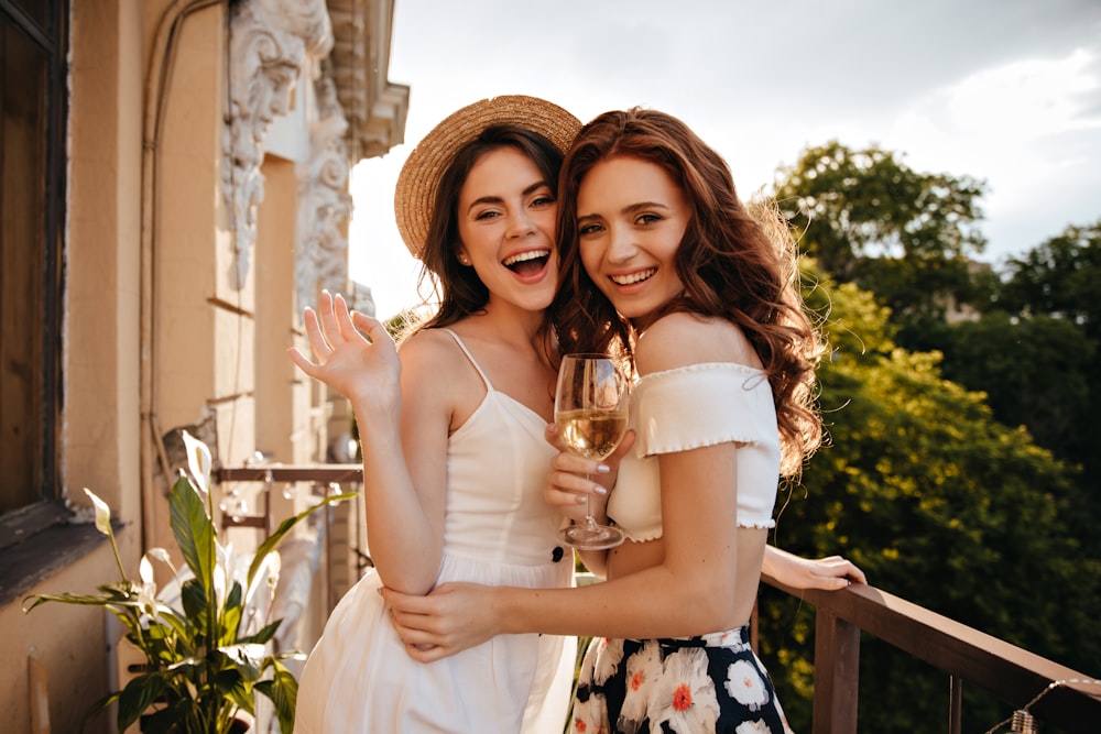 two women standing next to each other holding wine glasses