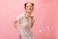 a woman standing in front of a pink background