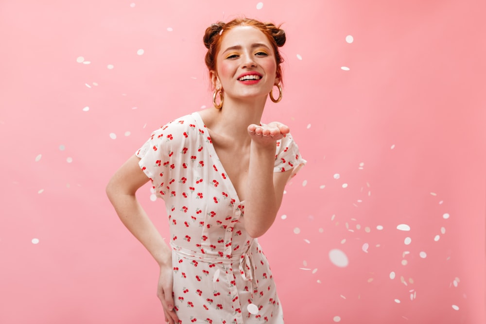 a woman standing in front of a pink background