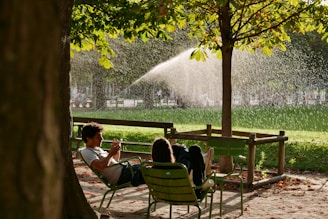 a man and a woman sitting on a bench under a tree