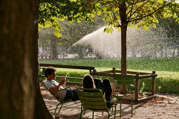 a man and a woman sitting on a bench under a tree