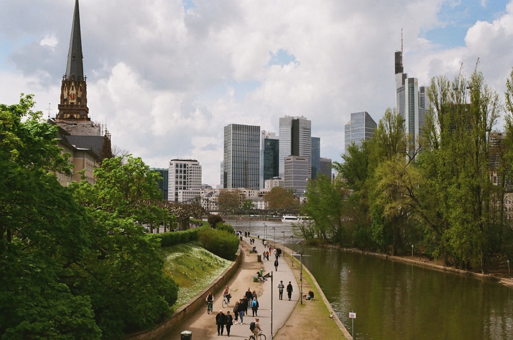 a group of people walking down a sidewalk next to a river