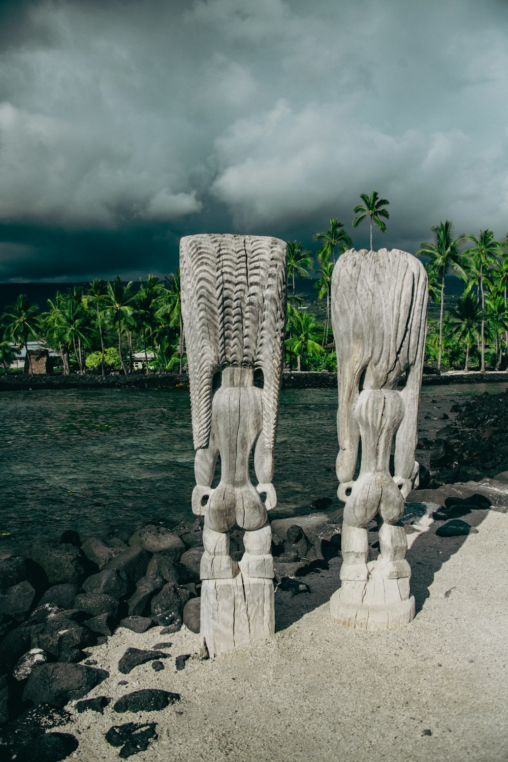 um par de estátuas sentadas no topo de uma praia de areia
