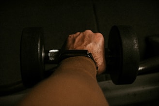 a person's hand holding a barbell in a dark room
