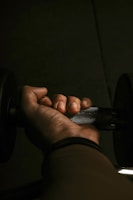 Close-up of muscular arms gripping a professional squat rack barbell under intense gym lighting.