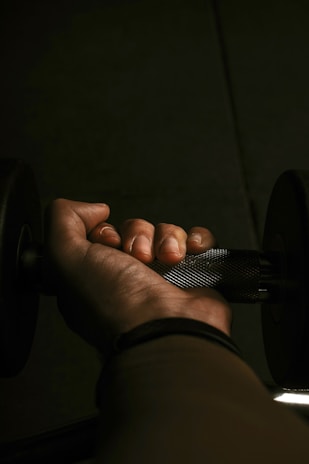 Close-up of a hand gripping a heavy dumbbell in a gym setting