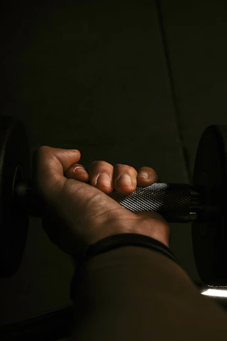 A close-up of a determined athlete gripping a black and red hand grip with intense focus